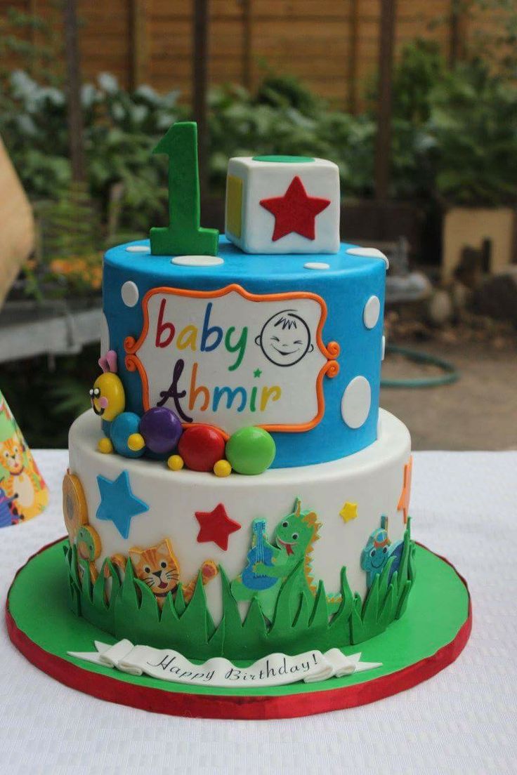 a multi layer cake decorated with animals, stars and numbers on a white table cloth