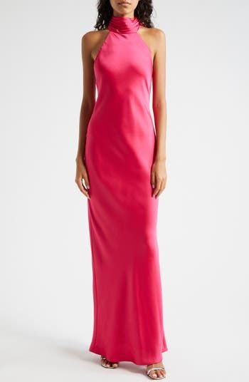 a woman in a long pink dress with halter neck and side slits, posing for