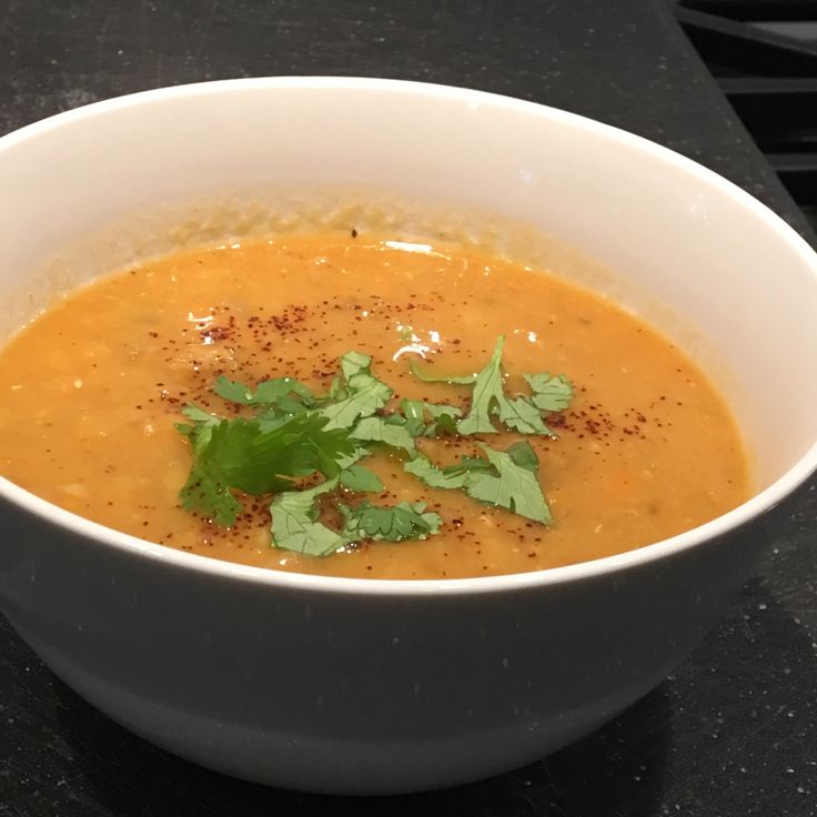 a white bowl filled with soup and garnished with cilantro