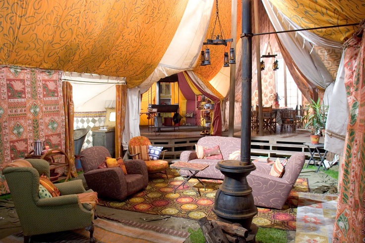 a living room filled with lots of furniture next to a fire place in a tent