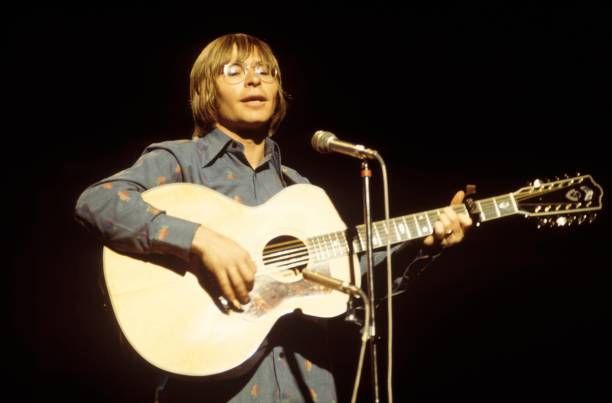 a man holding a guitar while standing in front of a microphone