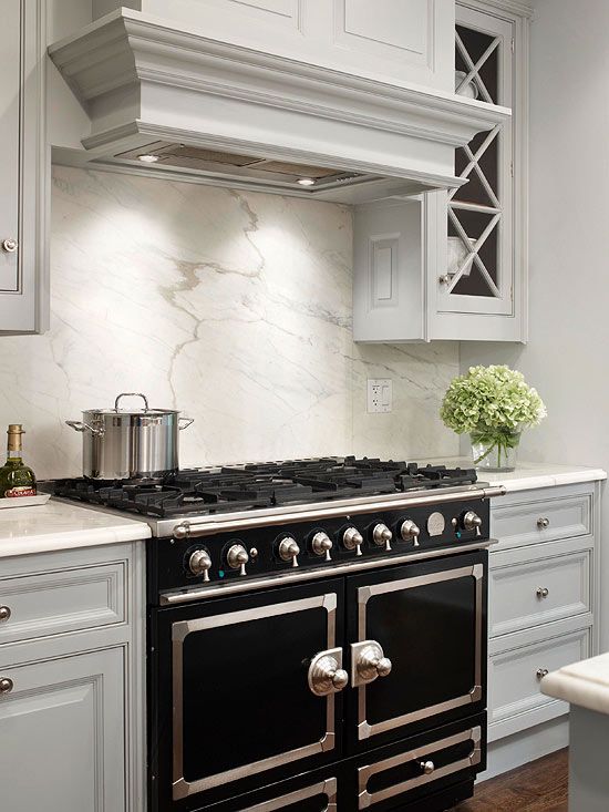 a stove top oven sitting inside of a kitchen next to white cabinets and counter tops