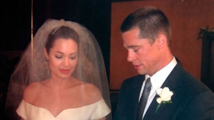 a man and woman standing next to each other in front of a wedding cake on a table