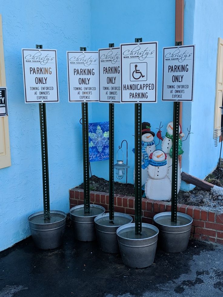 four buckets with signs on them sitting in front of a blue wall and some potted plants