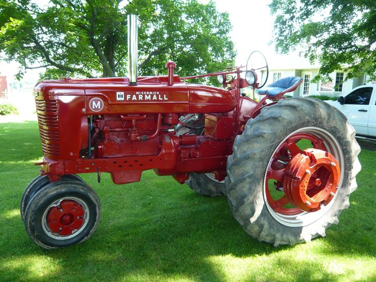 an old red farmall tractor parked in the grass