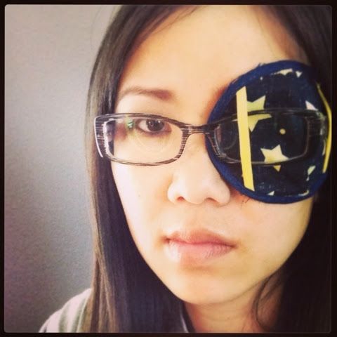 a woman wearing glasses with an eye patch in the shape of a cross on it