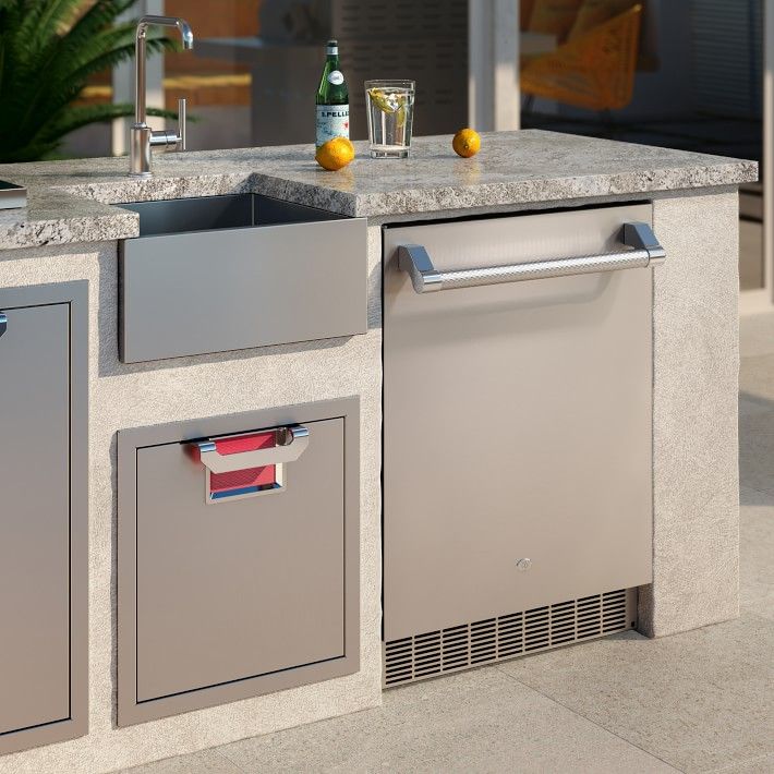 an outdoor kitchen with stainless steel appliances and granite counter tops, including two sink basins