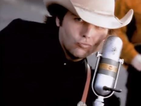 a man wearing a cowboy hat and holding a microphone