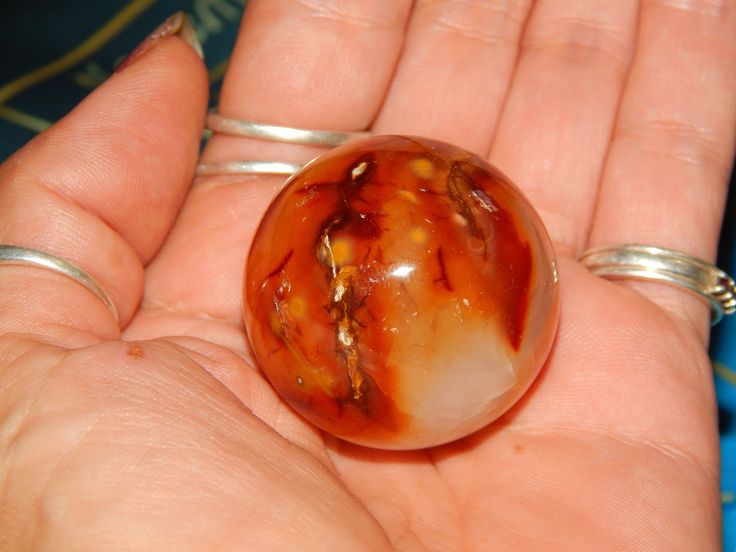 a close up of a person's hand holding a glass object in their palm