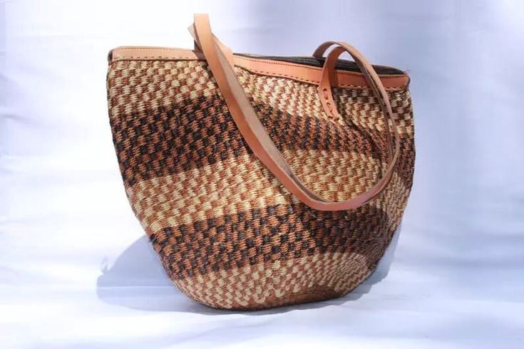 Tote bag, Woven Bag with Leather Handles, Beach Bag, Picnic Bag, Natural Bag, laptop bag, Office bag, Traveling bag This beautiful handmade Tote bag originated from craftsmen living in Eastern Community in Kenya, the Akamba. Our Tote bags are woven using colored sisal and leather hands.The woven bag is made from products which are entirely eco-friendly and sustainable, leather to provide comfort and padding. Leathers are naturally tanned from cows and camel. It has a zipper. This Tote bag is rea Brown Woven Tote Shoulder Bag, Casual Bucket Shoulder Bag With Weaving, Woven Jute Tote Beach Bag, Brown Weaving Straw Bag For Daily Use, Natural Weaving Tote Beach Bag, Casual Basket Shoulder Bag With Weaving, Natural Woven Beach Tote Bag, Casual Weaving Basket Shoulder Bag, Casual Basket Weave Shoulder Bag