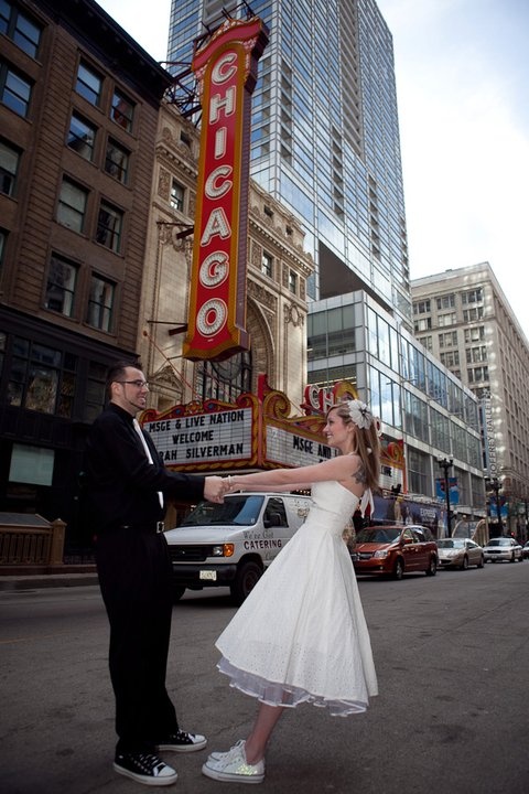 a bride and groom dancing in front of the chicago theater sign on their wedding day