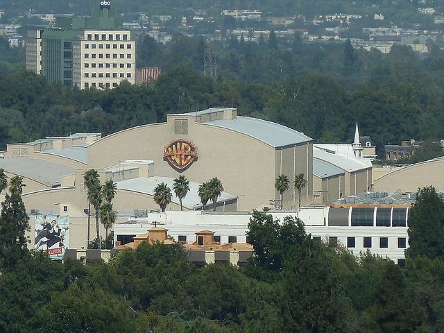 an aerial view of a building with trees in the foreground and buildings in the background