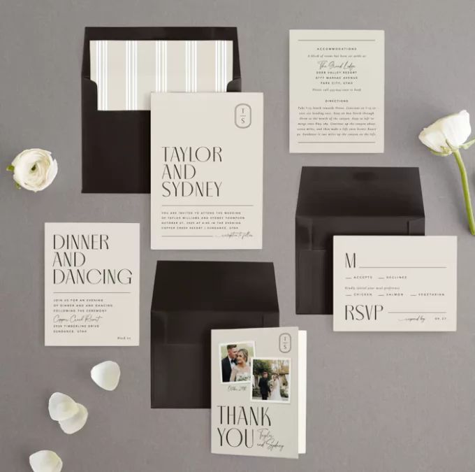 the wedding stationery is set up with black and white cards, envelopes, and flowers