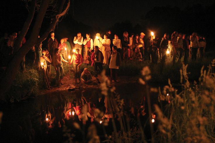 a group of people standing next to each other holding candles in their hands at night