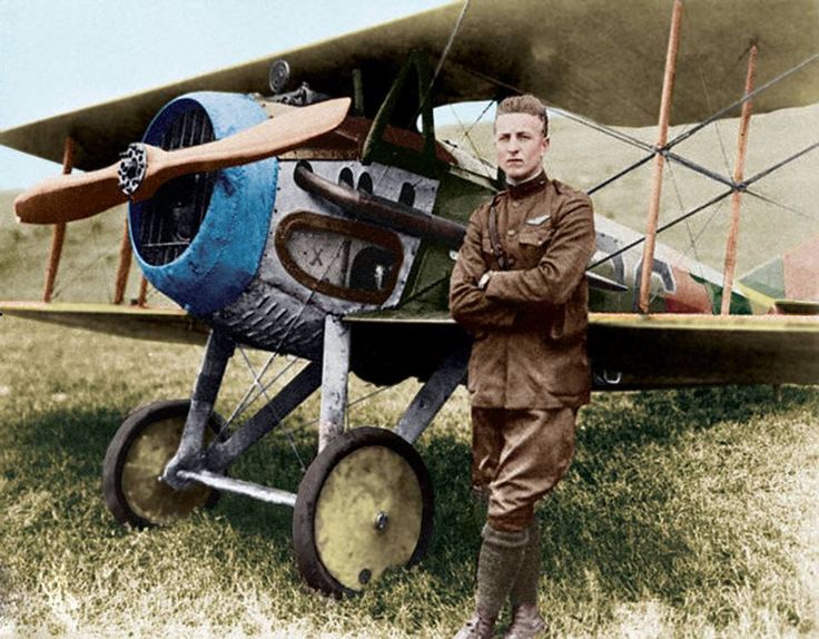 a man standing next to an old fashioned airplane