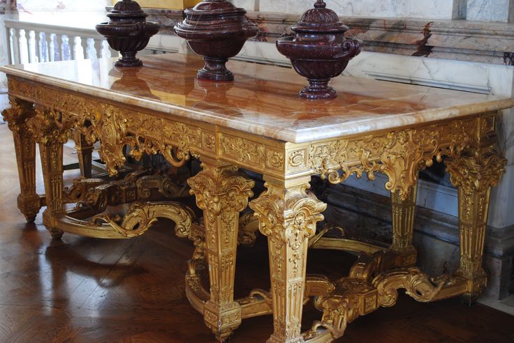 an ornately decorated table with three vases on top