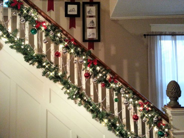 christmas garland on the banisters and stairs in a home decorated with red, green and white ornaments