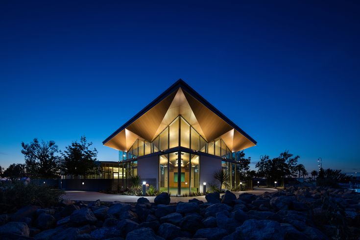 a modern building lit up at night with rocks in front