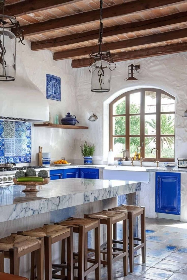 a large kitchen with blue and white tiles on the counter tops, wooden stools, and an arched window