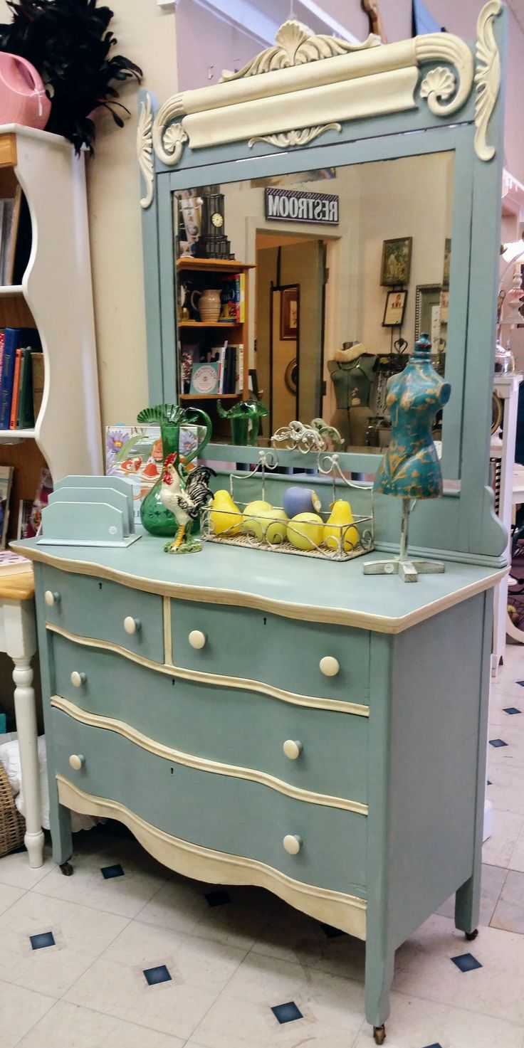 a blue dresser sitting in front of a mirror