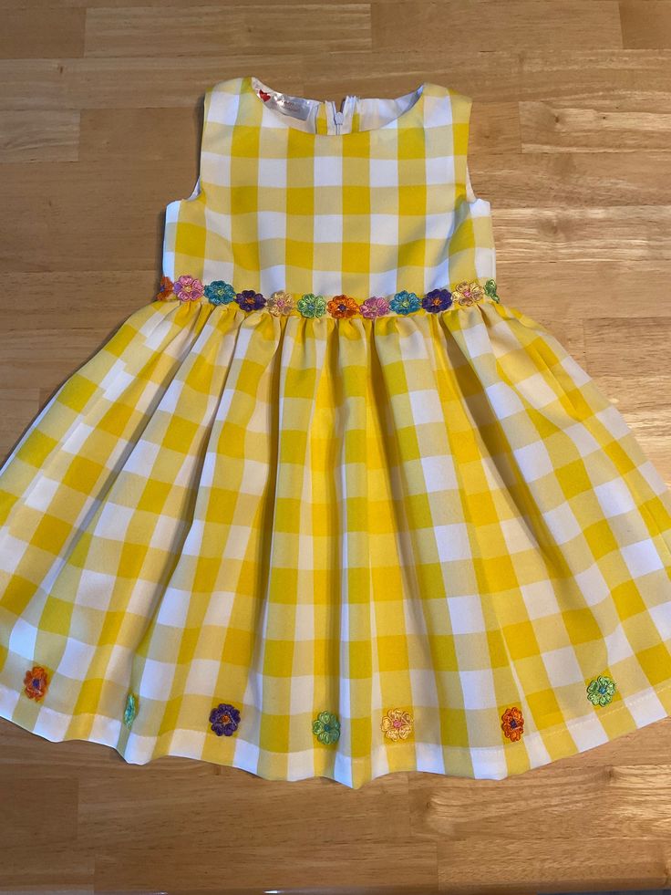 Yellow Large Checked Flowy Fabric, Full Skirt with Embroidered Flower Trim. Fits Sizes: 5-6, Below the Knee. Always 1 of a Kind. Yellow Cotton Sundress For Spring, Yellow Sundress For Spring Events, Playful Floral Embroidery Dress For Spring, Cute Fitted Yellow Dress, Cute Yellow Sundress For A Garden Party, Cute Yellow Sundress For Garden Party, Cute Yellow Dress For Garden Party, Spring Cotton Dress With Floral Applique, Playful Gingham Dress For Spring