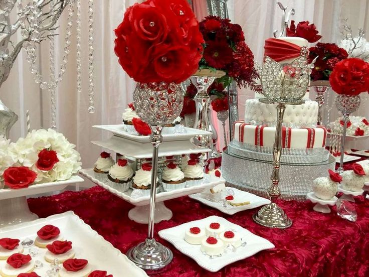 red and white desserts are on display at a wedding or reception table with flowers