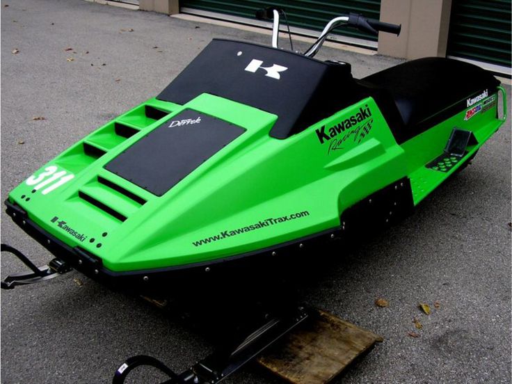 a green and black snowmobile parked on the street