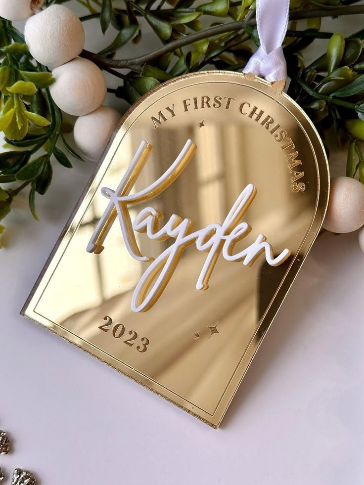 a gold christmas ornament with the name kayefn on it next to some ornaments