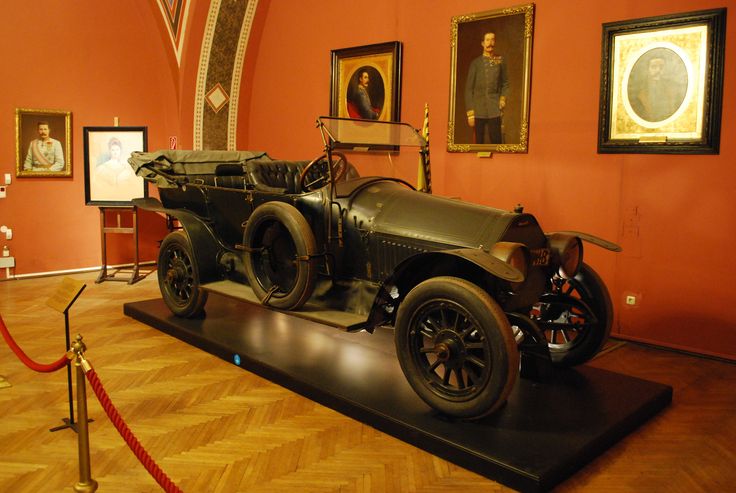 an old car is on display in a museum with other paintings and pictures around it