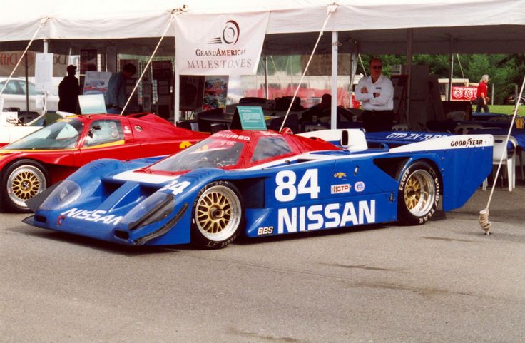 two race cars parked next to each other in front of a tent