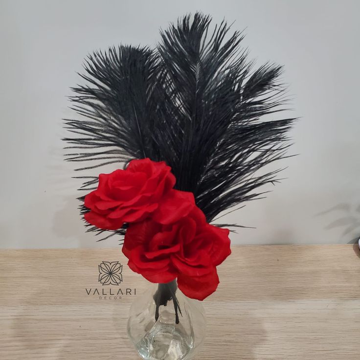 a vase filled with flowers and feathers on top of a wooden table