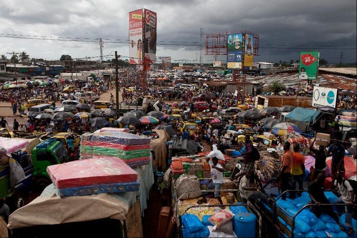 a large group of people standing around with umbrellas over their heads and luggage on the ground