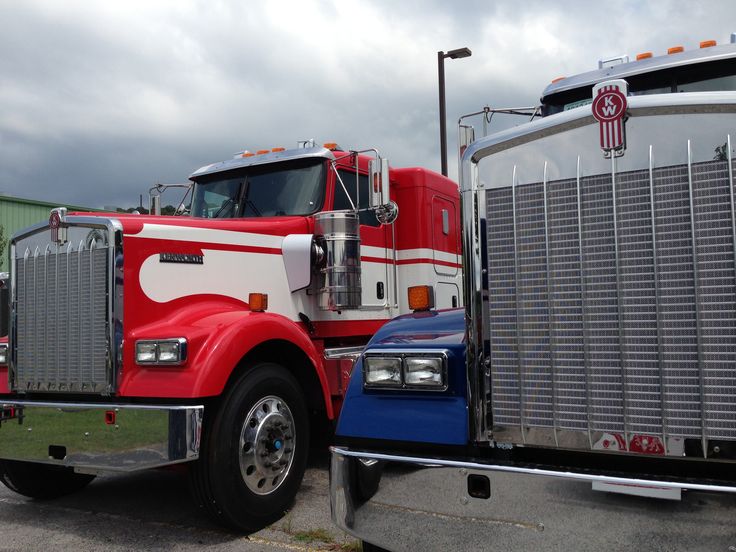 a red and white semi truck parked in a parking lot next to another semi truck