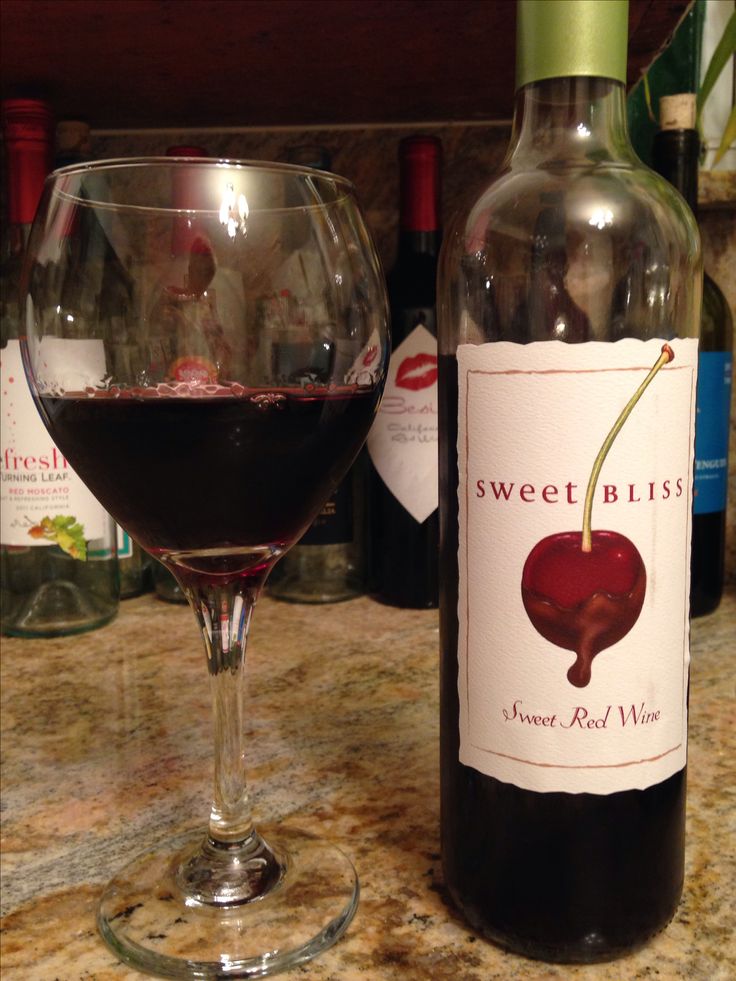 a bottle of wine next to a glass filled with red wine on top of a counter