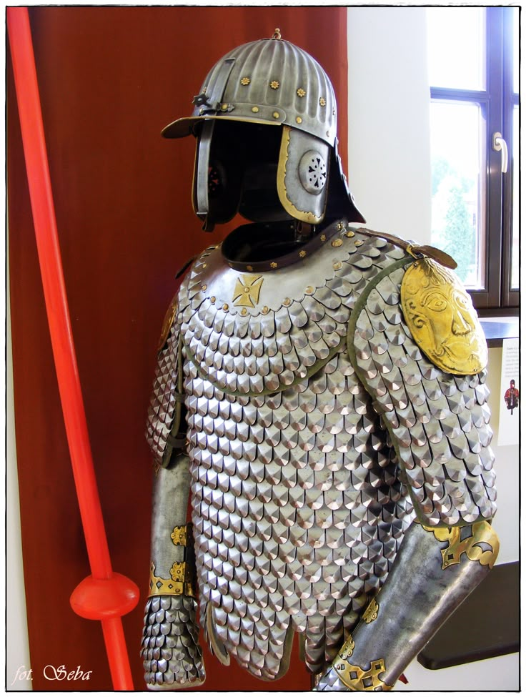 a knight armor and helmet on display in a room with a red pole behind it