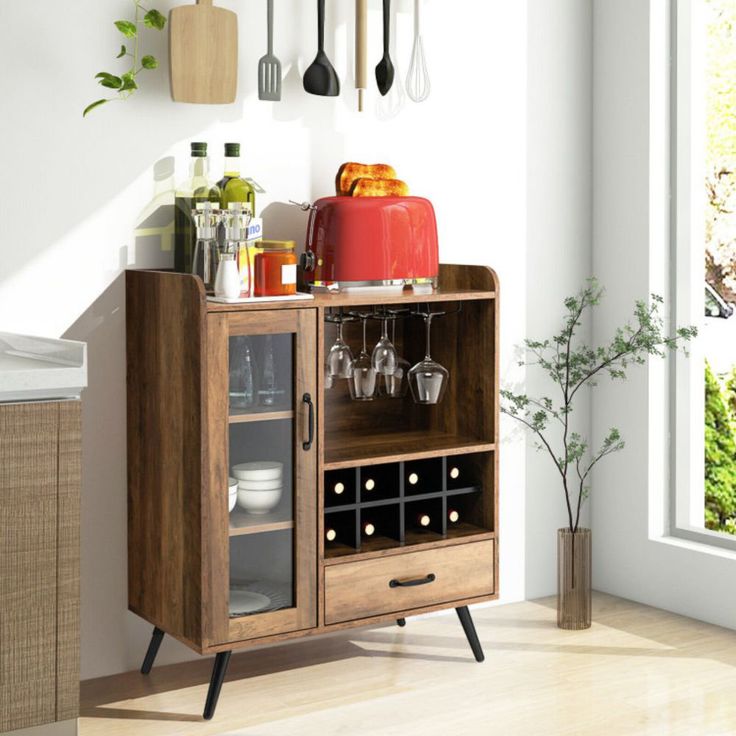 a wooden cabinet with wine glasses and utensils on the top, in front of a window