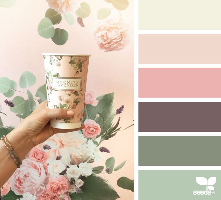 a person holding up a cup with flowers on it and the color scheme is pink