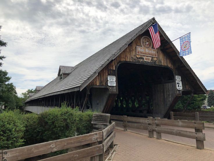 a wooden covered bridge with an american flag on top