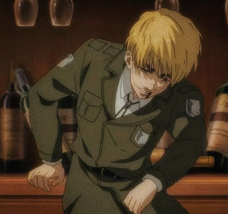 a young man in uniform leaning on a counter next to bottles and wineglasses