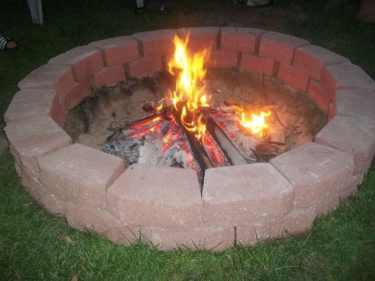 an open fire pit sitting on top of a lush green field