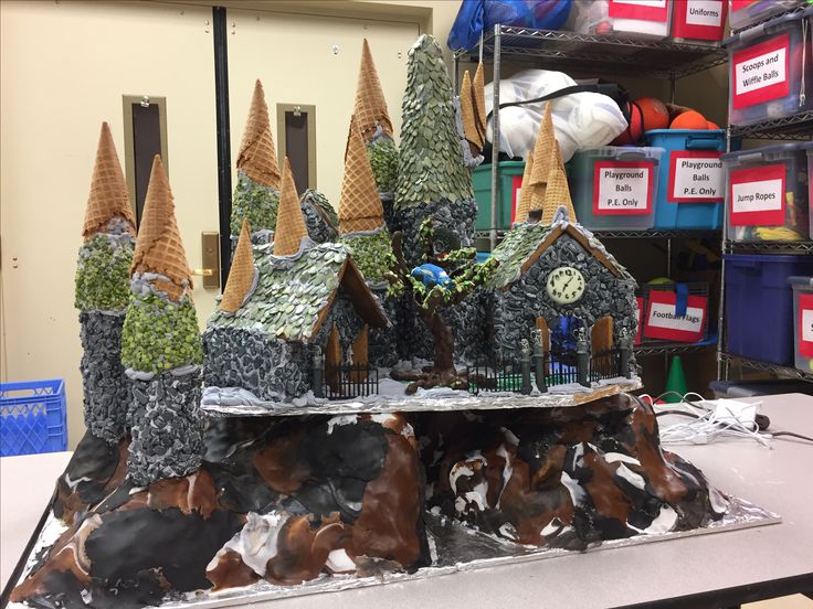 a table topped with lots of fake houses covered in frosting and trees on top of rocks