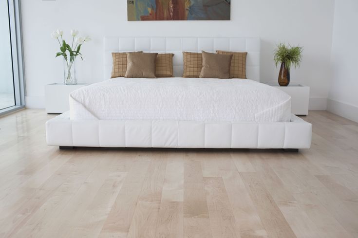 a large white bed sitting on top of a hard wood floor