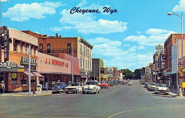 an old photo of a city street with cars parked on the side walk and stores