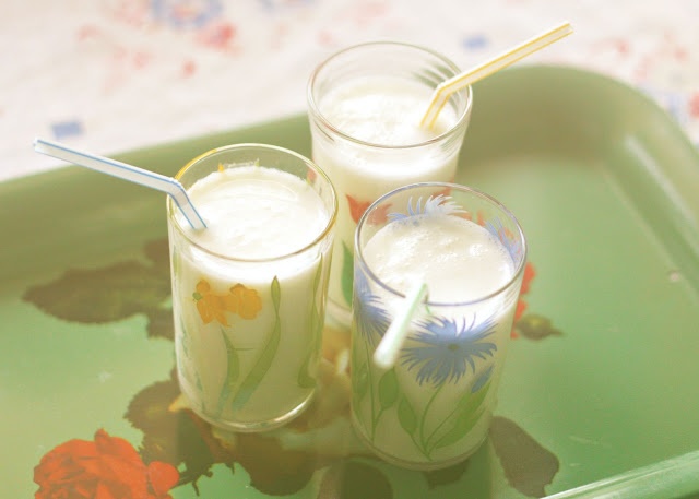 three glasses filled with milk sitting on top of a green tray