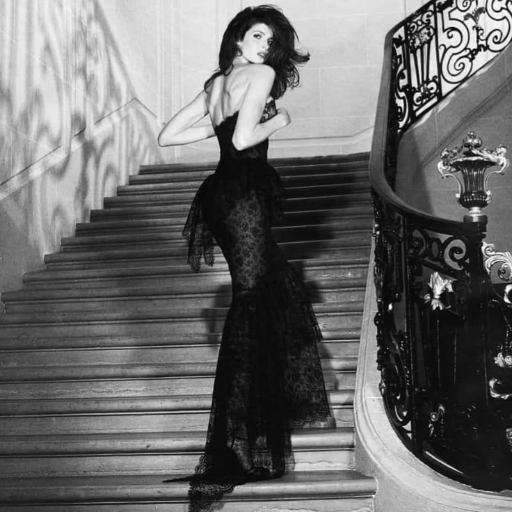 a woman in a black dress standing on some stairs