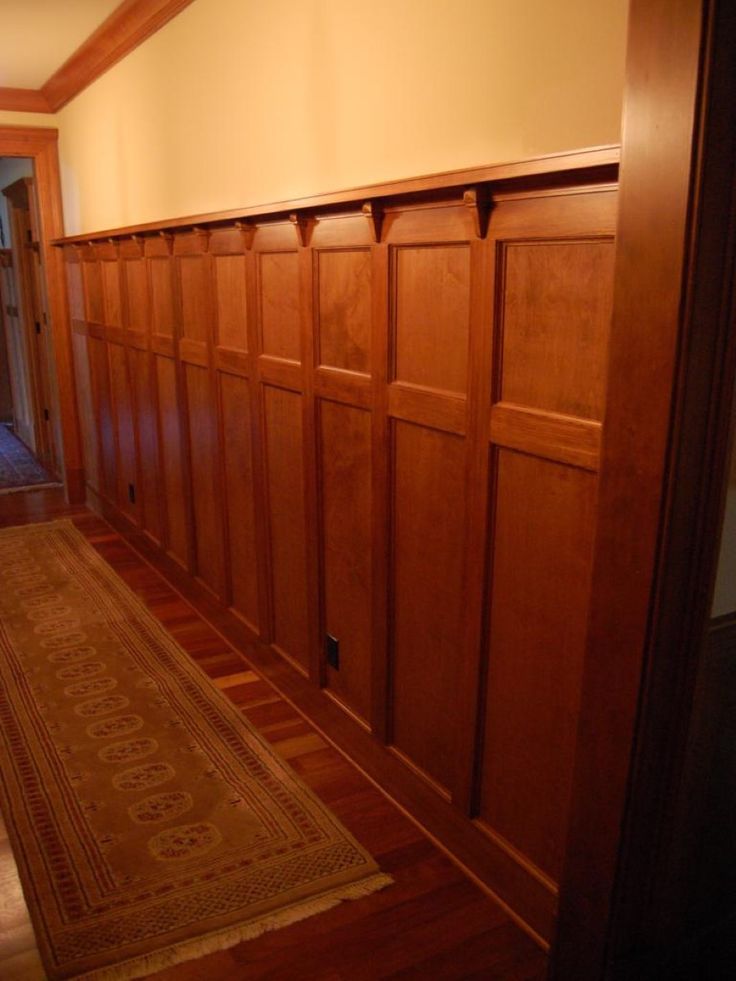 an empty hallway with wooden paneling on the walls and carpeted floor, in front of a doorway