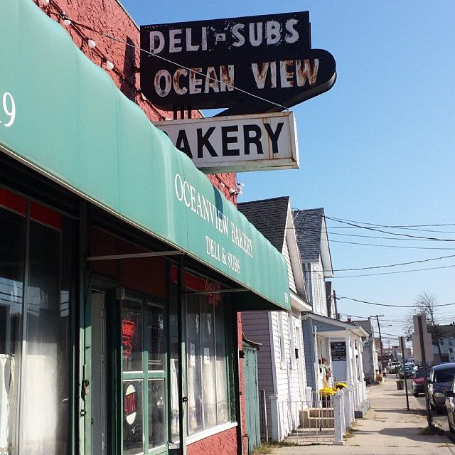 the sign for deli and subs ocean view bakery is hanging from the side of the building