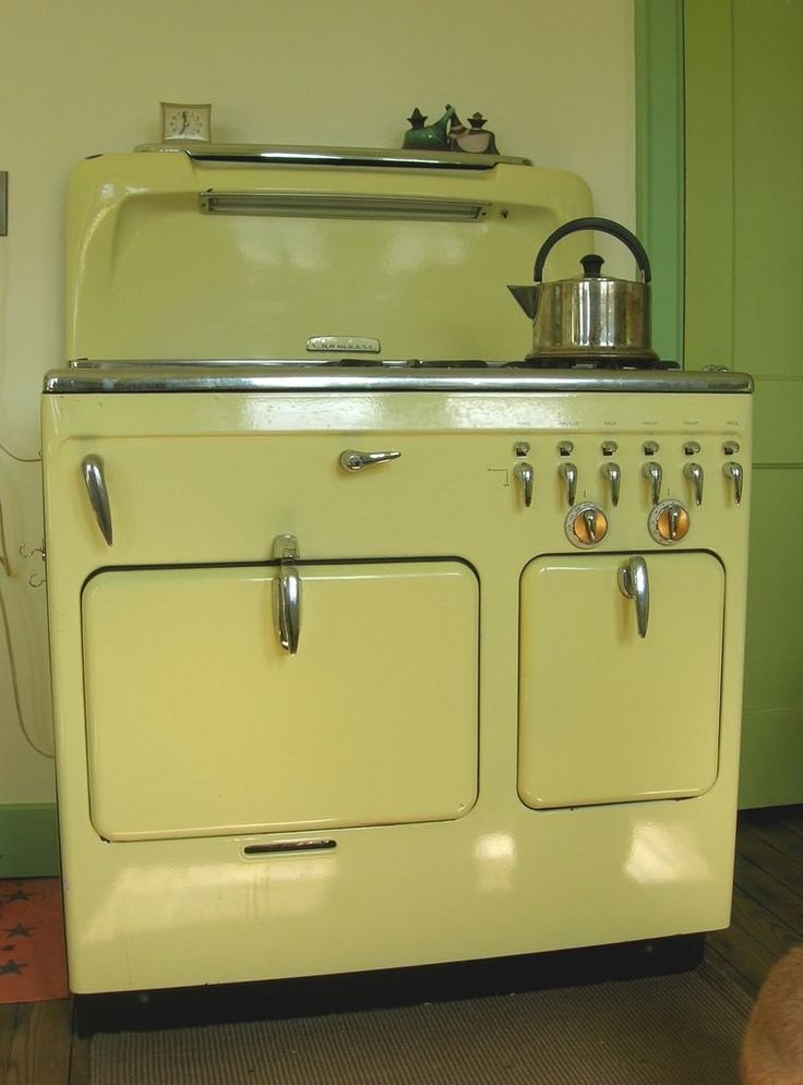 an old fashioned yellow stove with a pot on it's burner and oven door