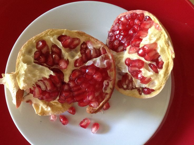 two pomegranates sitting on top of a white plate