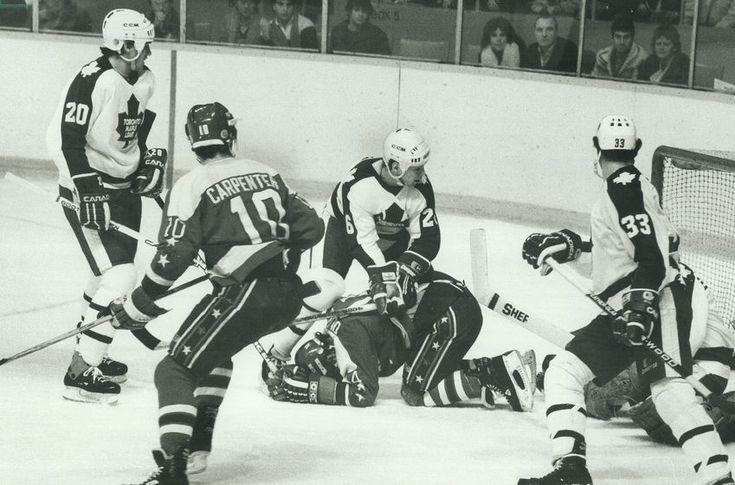 an old black and white photo of hockey players on the ice during a game with fans watching